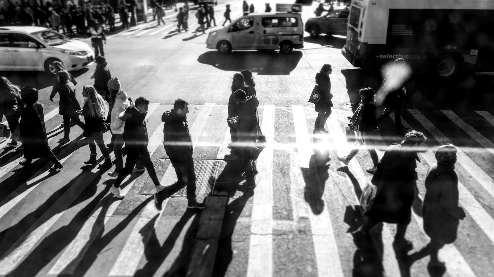 Une foule traverse un passage piéton, photographiée d'en haut en noir et blanc